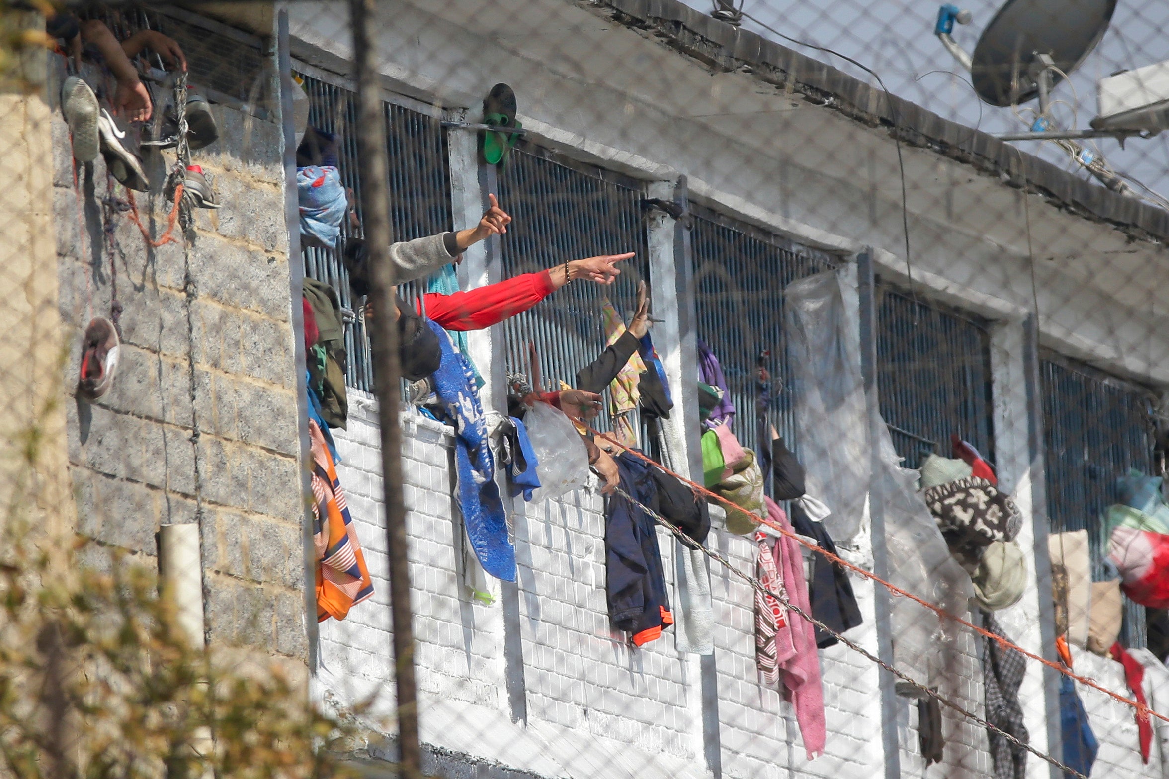Inmates point from inside of La Modelo prison in Bogota, Colombia, Sunday, March 22, 2020.