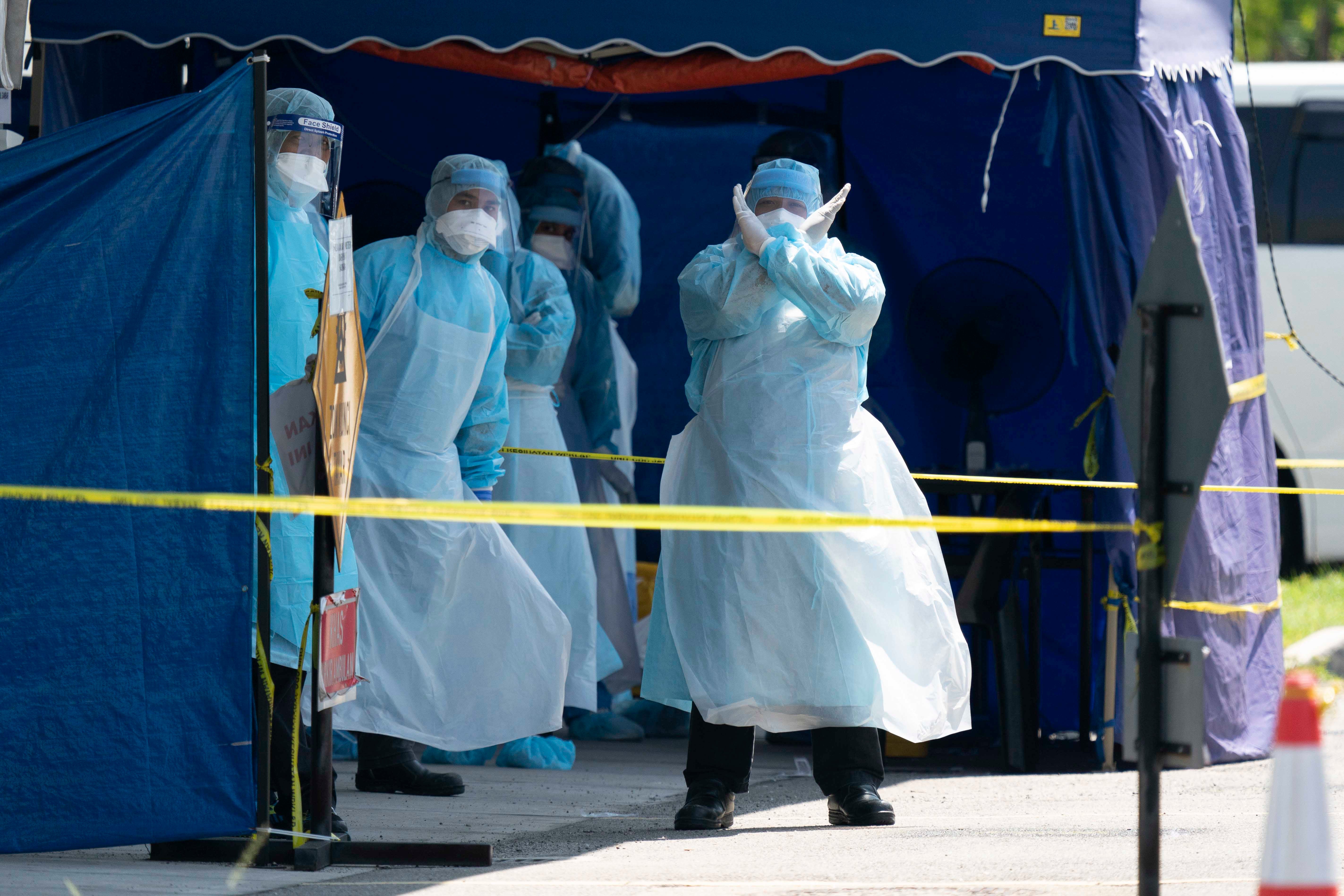 A health worker in a protective suit gestures in a tent erected to test for the new coronavirus at a clinic in Kuala Lumpur, Malaysia, March 24, 2020.  