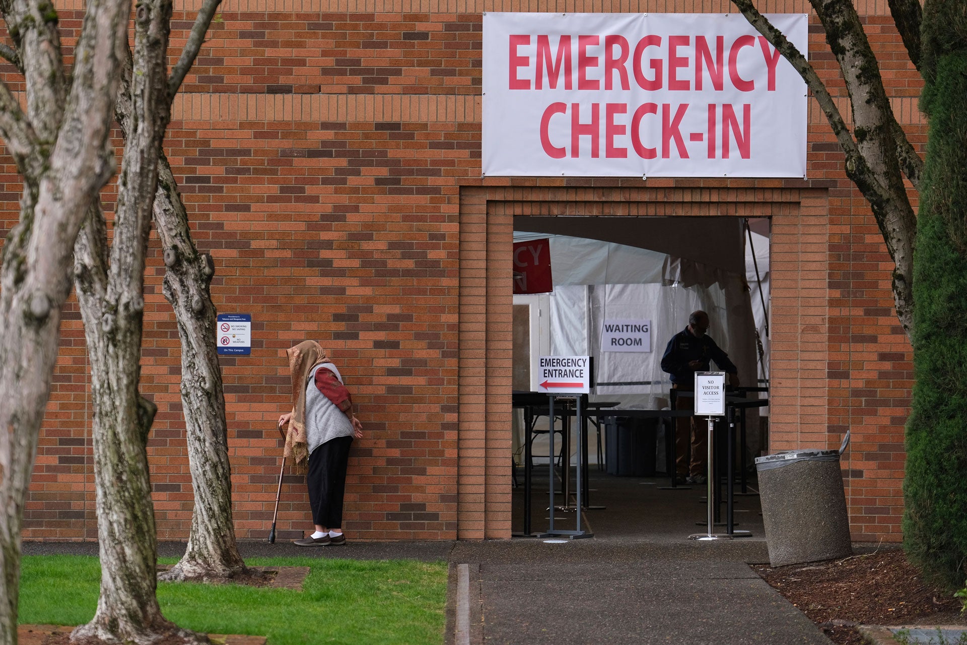 A woman waits outside the emergency check-in entrance at the Providence Medical Center in Portland, Ore., on March 24, 2020. 