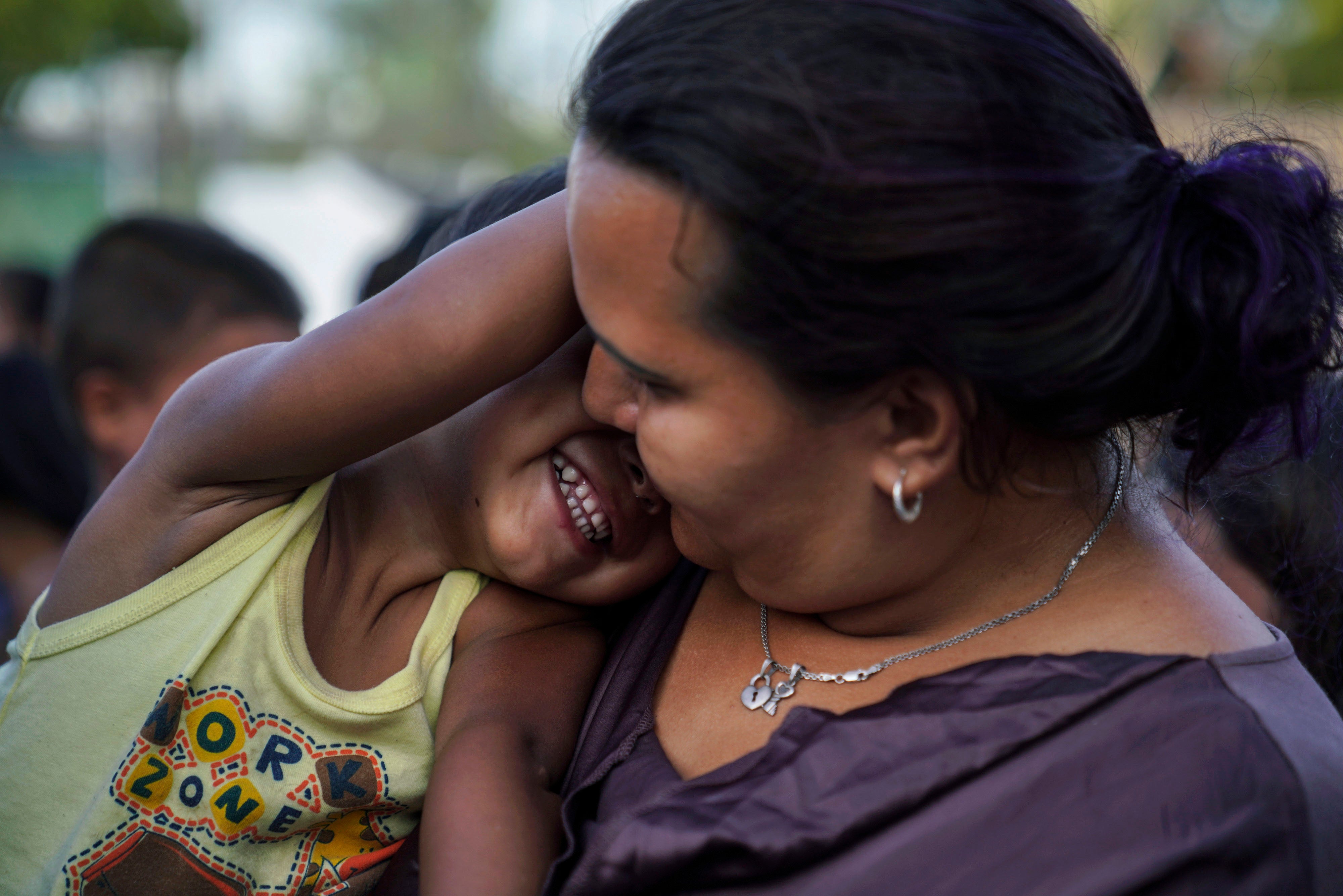 A Honduran mother plays with her son as they wait in line to get a meal in an encampment near the Gateway International Bridge in Matamoros, Mexico, August 30, 2019.