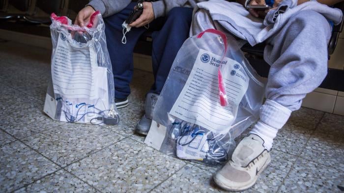 Aslyum seekers hold bags from the Department of Homeland Security