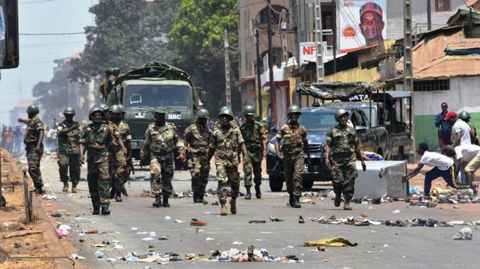 Uniformed soldiers march down a city street 