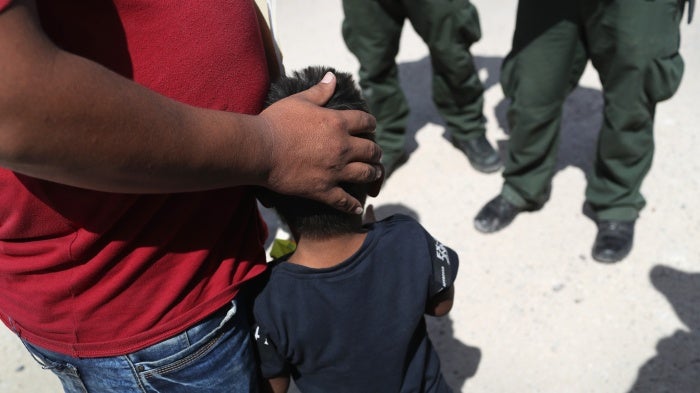 A father embraces his son in front of border agents
