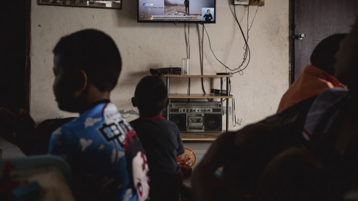 Children watch news reports about the situation along the Thai-Cambodian border, in Sisaket province in northeastern Thailand, July 27, 2025.