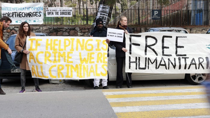 Protesters hold signs outside a Greek court in Mytilene