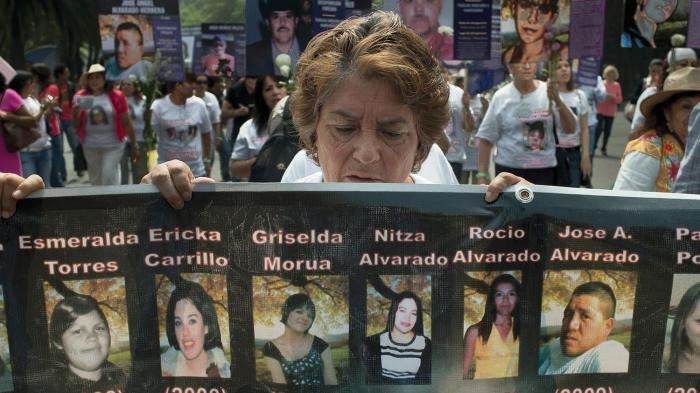 A woman carries a banner bearing photographs of missing persons in a march by mothers of the disappeared in Mexico City, May 10, 2012.