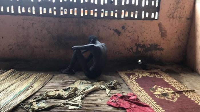 A man sits on the ground in shadow