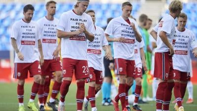 Members of a football team wear t-shirts calling for human rights for migrant workers 
