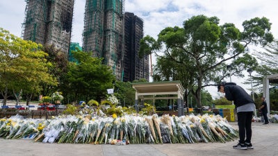 Flower offering in front of burnt buildings, woman praying