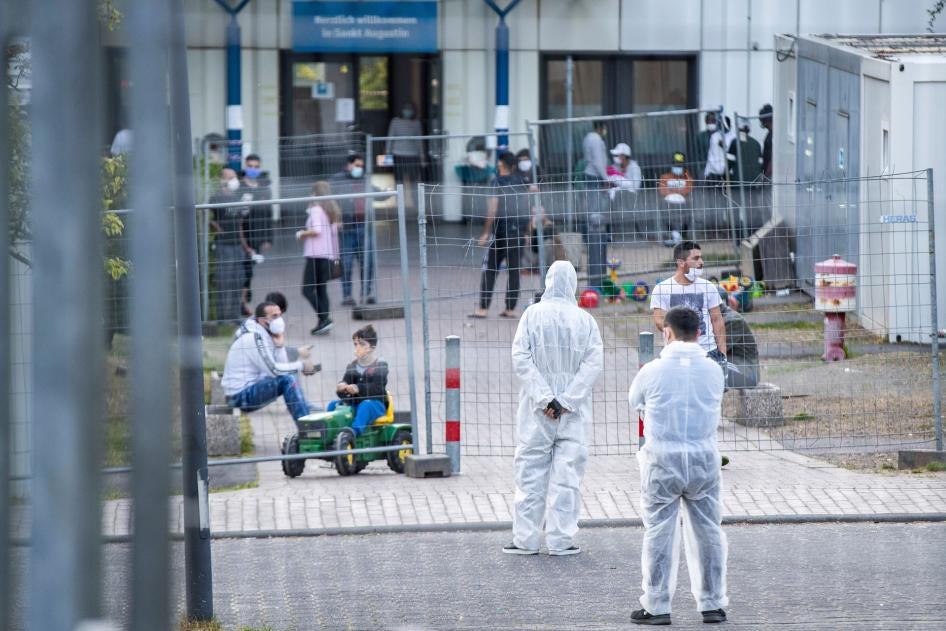 Members of a security service stand in protective gear inside a reception center for asylum seekers in North Rhine-Westphalia where 70 people tested positive for the virus that causes Covid-19, May 17, 2020. 