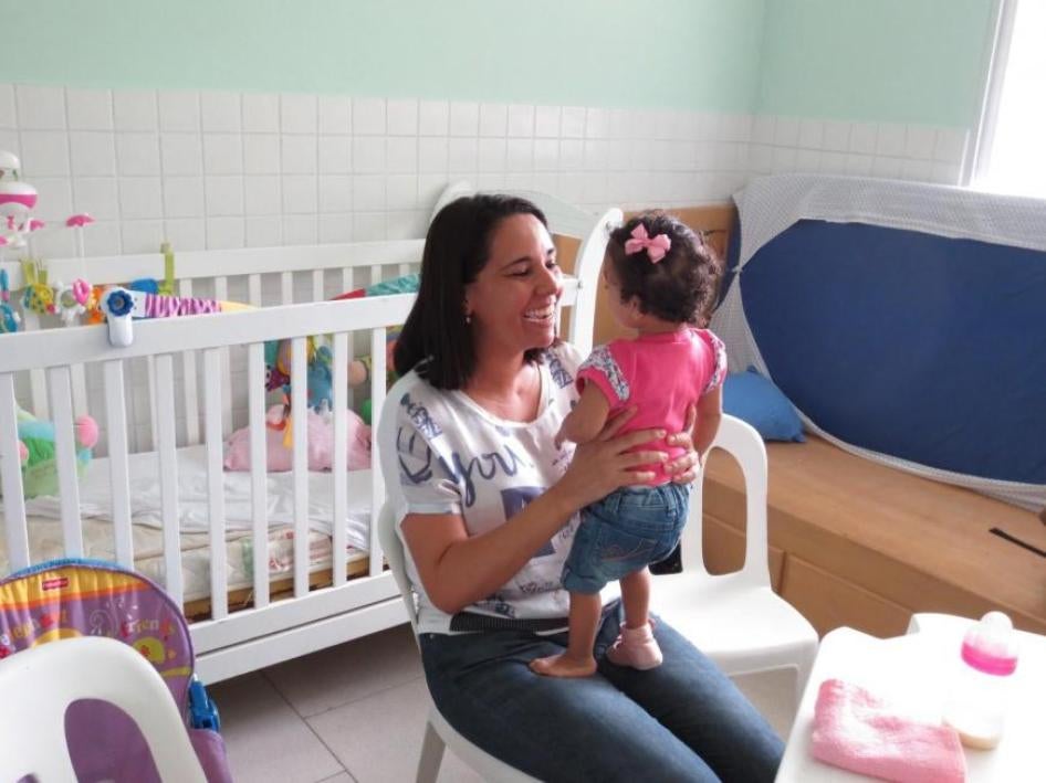 Uma mãe com sua filha adotiva de 3 anos que tem deficiência de desenvolvimento.