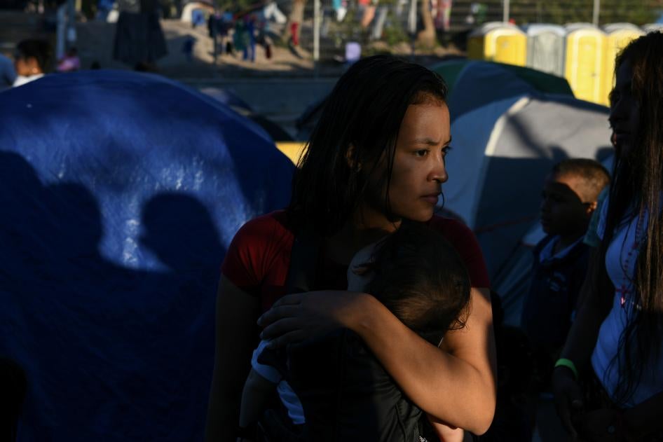 A Honduran migrant mother and child wait in line for a dinner provided by volunteers at a makeshift encampment occupied by asylum seekers sent back to Mexico from the US in Matamoros, Tamaulipas, Mexico, October 27, 2019.  