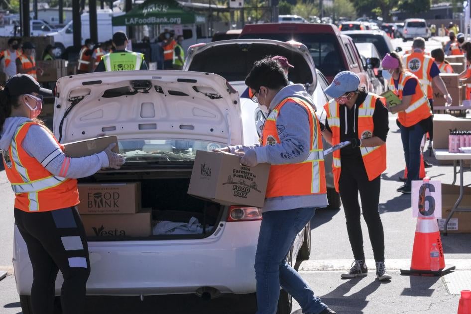 Volunteers load food into the trunk of vehicles during a ''Let's Feed LA County'' drive-thru food distribution by the Los Angeles Regional Food Bank and the office of Supervisor Hilda Solis on February 23, 2021, in La Puente, California.