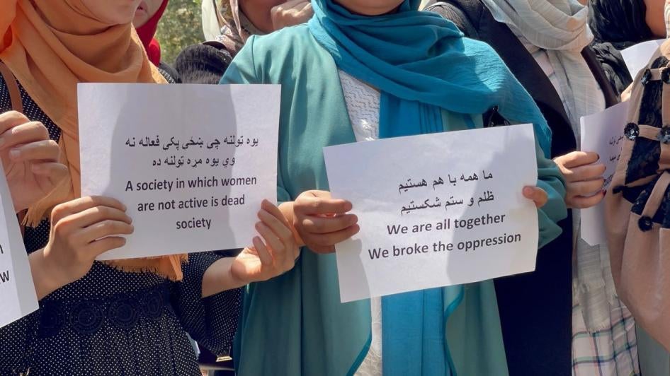 Two women hold protest signs 