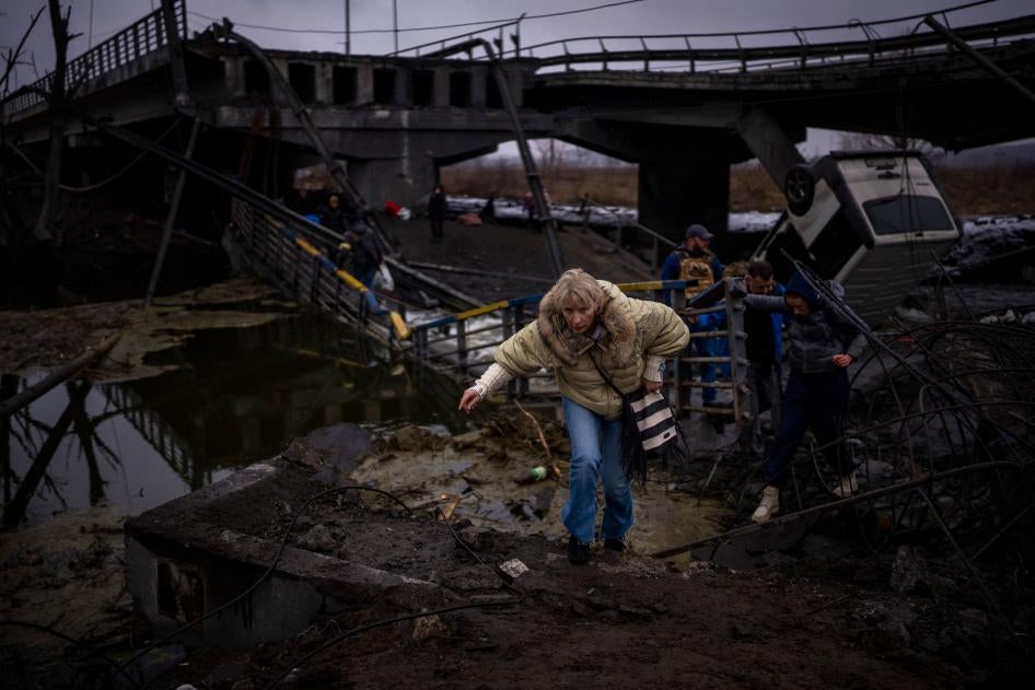 People flee across a destroyed bridge on the outskirts of Kyiv, Ukraine, March 2, 2022.