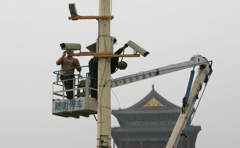 Labourers adjust newly installed surveillance cameras at Tiananmen Square ahead of National Day on September 28, 2005.