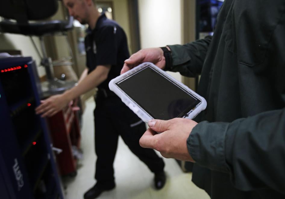 A prisoner holds a tablet that he checked out from a corrections officer, left, at the New Hampshire State Prison for Men, in Concord, N.H., July 23, 2018. © 2018 Charles Krupa/AP Photo
