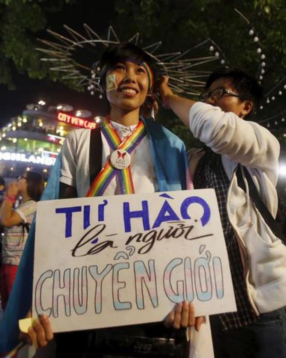 A participant holds a placard which reads "proud to be transgender" as they wait for an LGBT demonstration along a street in Hanoi.