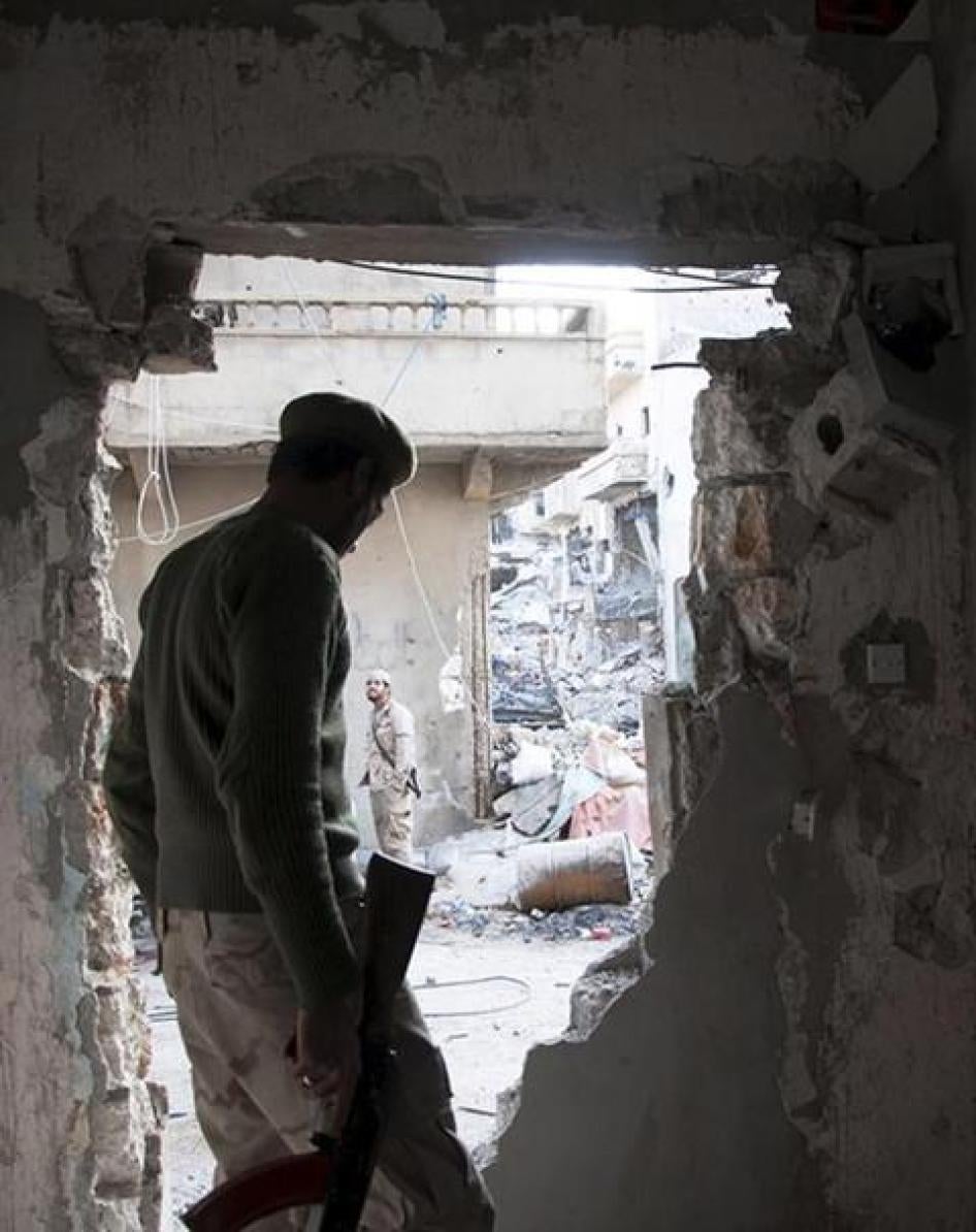 A member of the Libyan National Army, the armed forces allied with the Interim Government in al-Bayda, stands next to a hole on a wall during clashes with the Benghazi Revolutionaries Shura Council, an Islamist militia alliance, in Benghazi, Libya. 