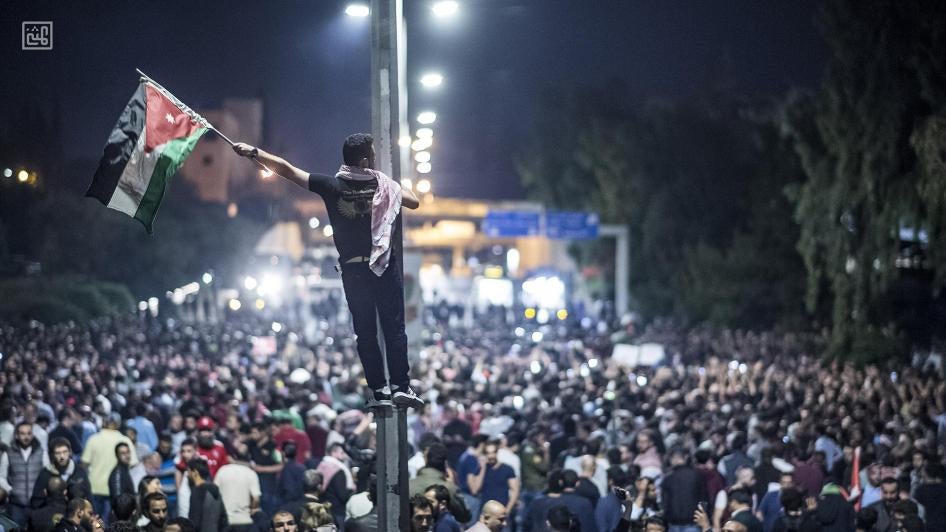 Protestor raises the Jordanian flag during 2018 protest in front of the prime ministry building in Amman