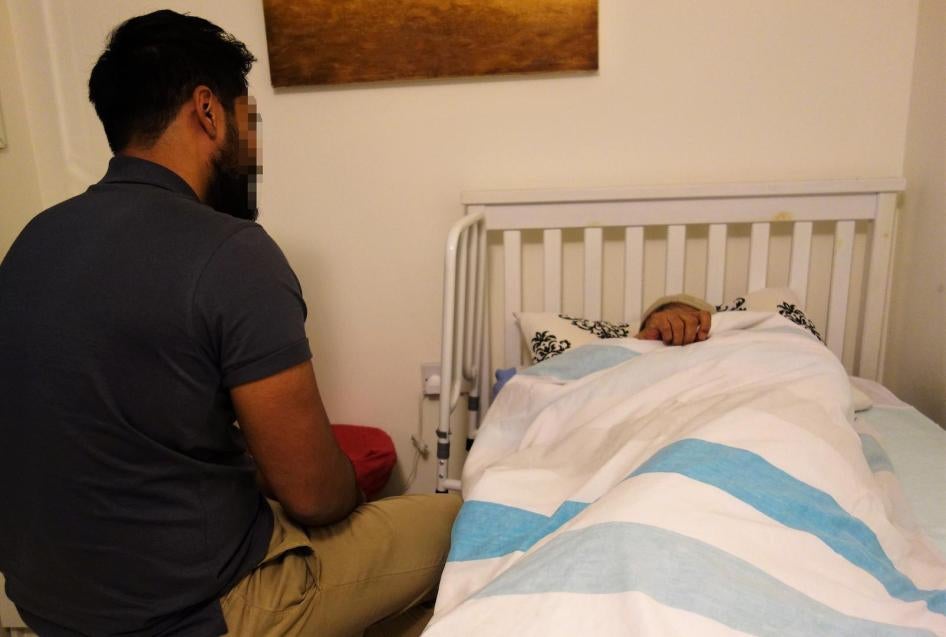 Mohammed sits with his father, Farhaz, at their home in east London. Farhaz suffers from severe dementia.  © 2018 Stephanie Hancock/Human Rights Watch