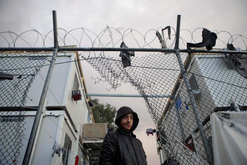 A boy stands next to a hole in the fence of the Moria camp following rainfall, on the island of Lesbos, Greece, November 22, 2019. REUTERS/Elias Marcou