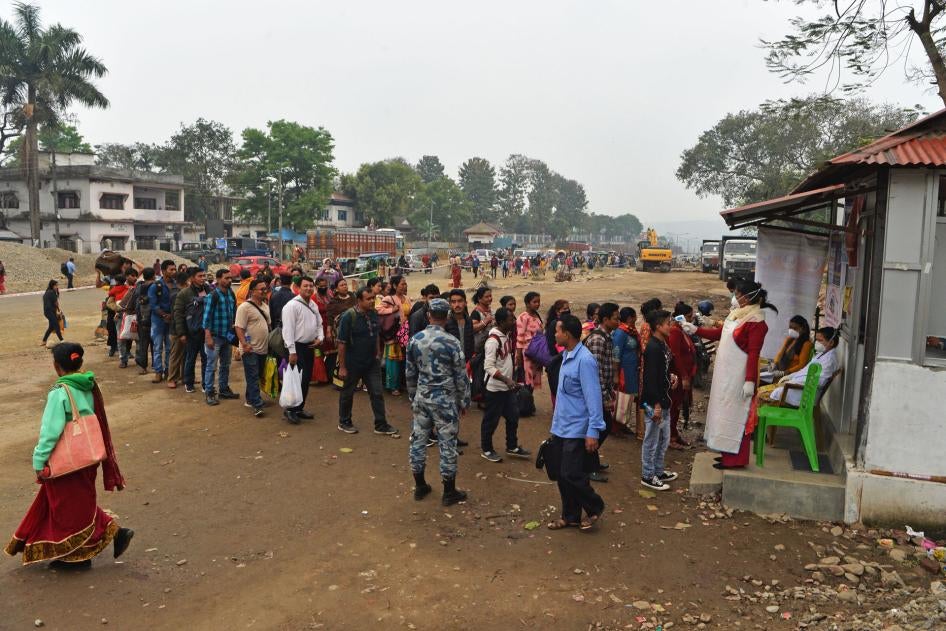 A member of medical staff wearing a facemask amid concerns over the spread of the COVID-19 novel coronavirus, checks the body temperature of travellers arriving from India at the eastern border with Nepal in Kakarvitta, March 14, 2020. 