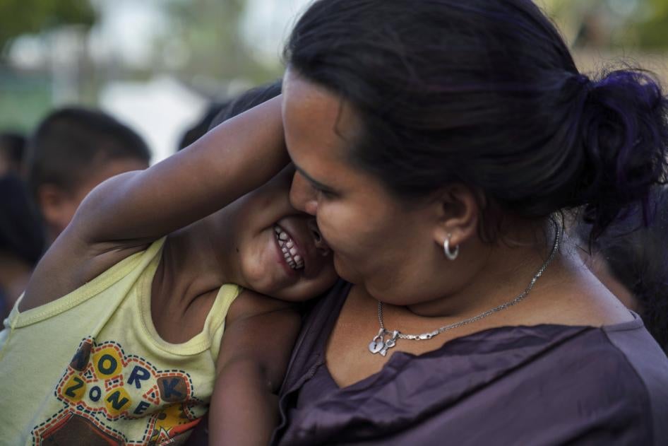 A Honduran mother plays with her son as they wait in line to get a meal in an encampment near the Gateway International Bridge in Matamoros, Mexico, August 30, 2019.