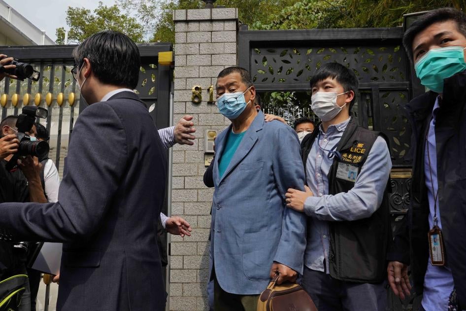 Jimmy Lai, center, Hong Kong media tycoon and founder of local newspaper Apple Daily, is arrested by police officers at his home in Hong Kong, April 18, 2020. 