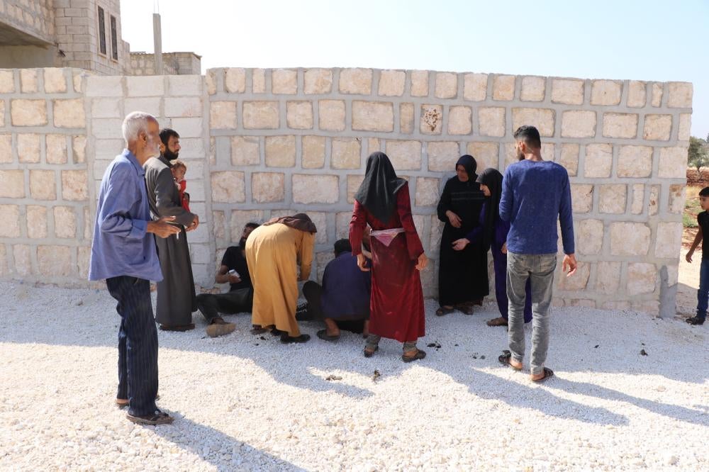 People gather around one of three people injured on October 7, 2023, after a nine-year-old picked up an unexploded submunition that detonated after he  dropped it the ground. The boy was severely injured, Termanin, Syria. 
