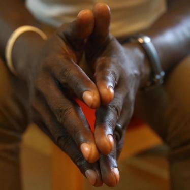 Clasped hands of interviewee are in focus in the foreground of the image