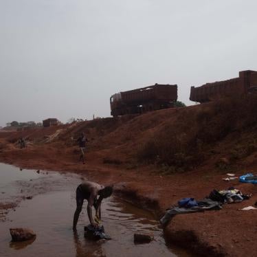 Man Washing Clothes Near Bauxite Mining