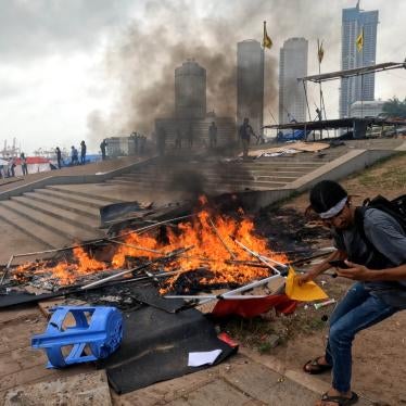 A Sri Lankan anti-government protester tries to save some papers from a tent that was set on fire