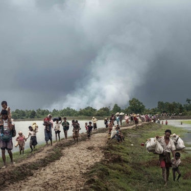 Refugees walk next to a river