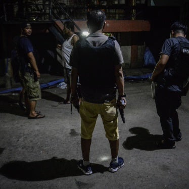 Policemen in plainclothes patrol a dark alley near the scene where three men were killed during a police anti-drug operation in Caloocan, Metro Manila, Philippines. 