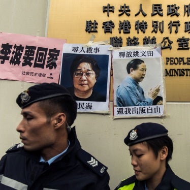 Police walk past missing person notices for Swedish publisher Gui Minhai (L) and Hong Kong publisher Yau Wentian, posted on the sign of China's Liaison Office in Hong Kong, January 3, 2016.