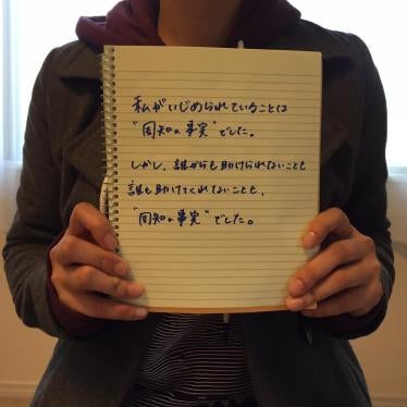 A 20 year old Japanese woman who was bullied by her classmates in junior high school holds a notebook displaying the message...