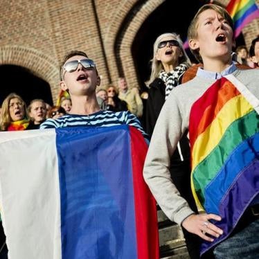 People sing the Russian national anthem while raising rainbow flags and a Russian flag in solidarity with the lesbian, gay, bisexual and transgender (LGBT) community of Russia