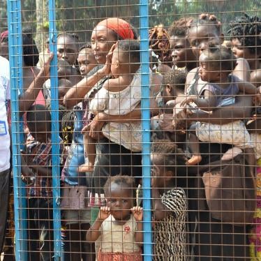 Staff members (left) of the International Organisation for Migration (IOM) assist Congolese migrants, who were living in Angola, to cross the border near the Congolese town of Kamako as they return to their country following a security crackdown by Angola