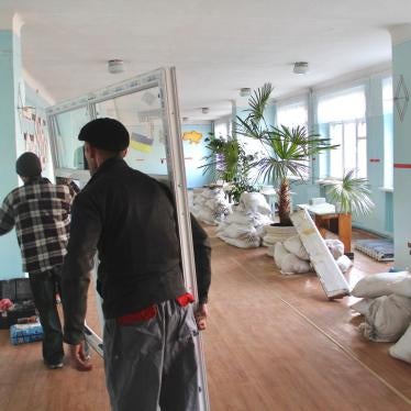 Two men carry replacement windows through a school in eastern Ukraine. The old windows were blown out when the school was hit by an explosive weapon